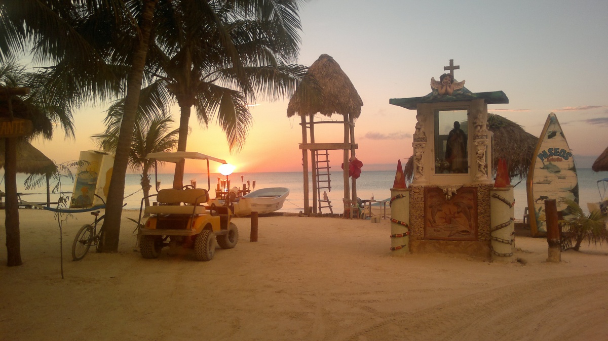 Terreno en venta en isla holbox - Playa al atardecer con palmeras, carrito de golf y torre de vigilancia frente al mar